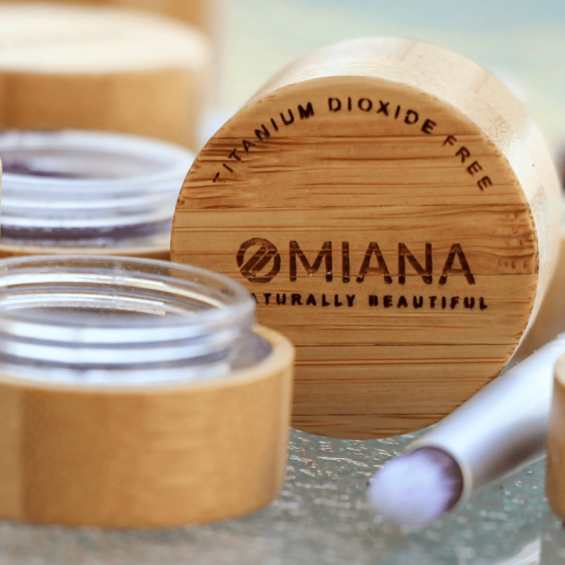 Mineral makeup Cosmetic jar with bamboo wooden lid and Omaina branding on a marble surface